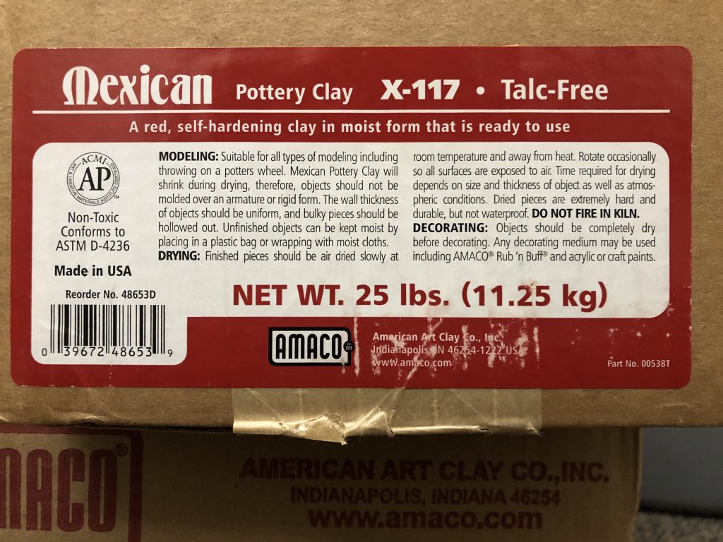 Photograph showing a close up view of a red and white label on a cardboard box. The label is for Mexican Pottery Clay.