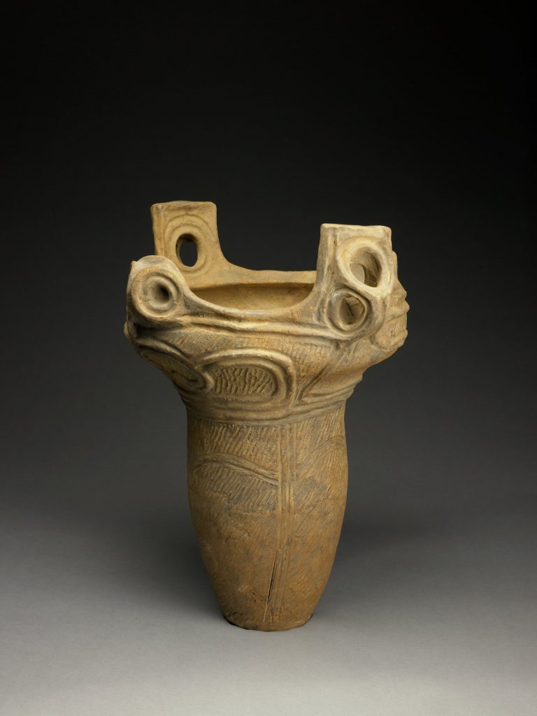 Photograph of a sculpture of a jar-like vase that is wider at the top where it opens up.