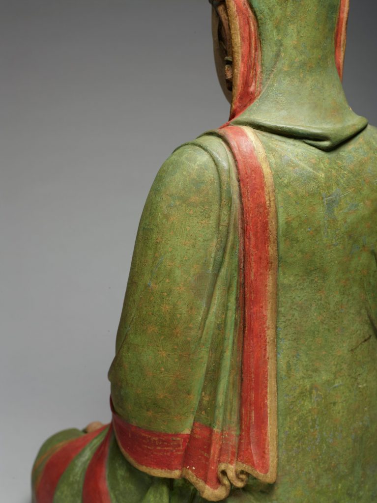 Photograph showing a close-up view of a sculpture; the photograph is showing a close-up view of the back of a person sitting.