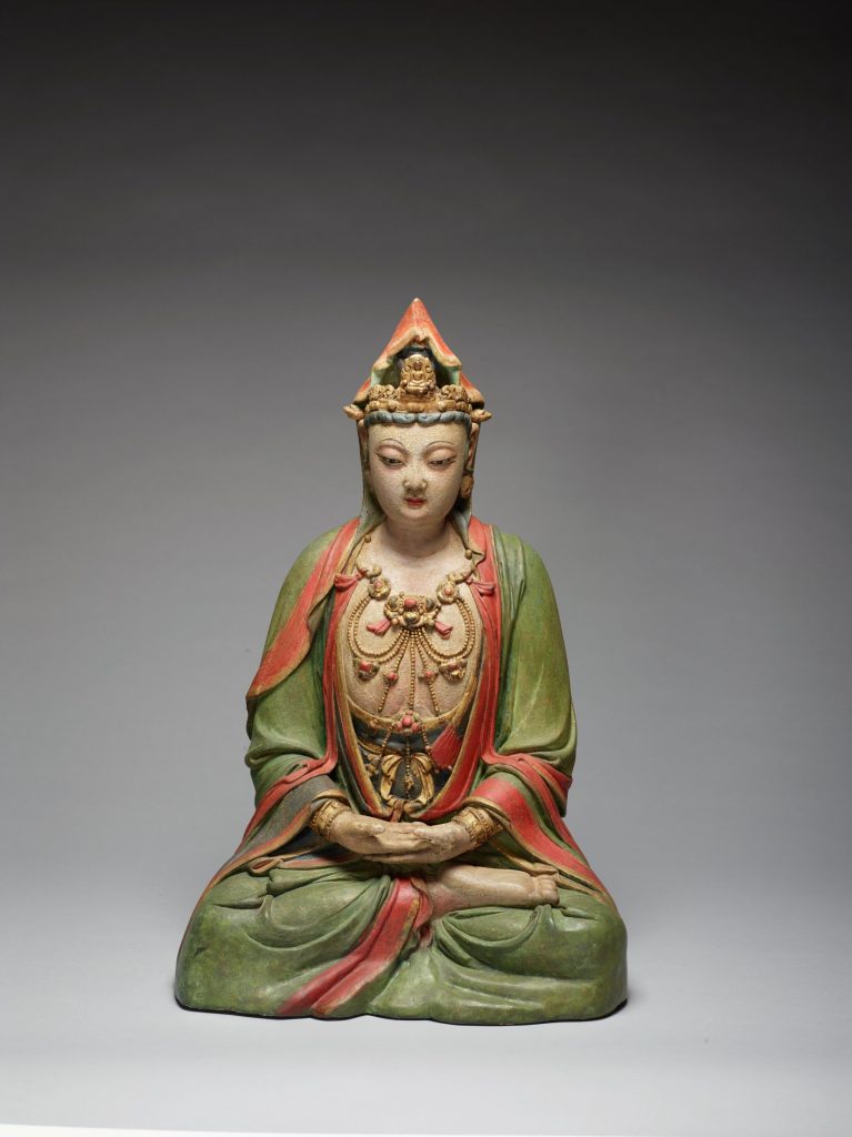 Photograph showing the front view of a sculpture of a Chinese mythological goddess sitting cross-legged with her hands resting in her lap. She is wearing a green and red robe and a triangular headpiece.