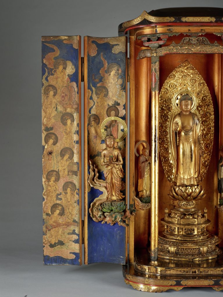 Photograph showing a large sculpture depicting a golden shrine-like structure with three statues and ornate details.
