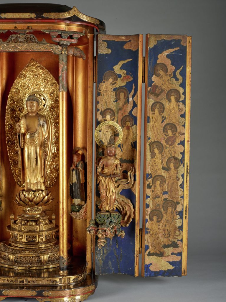 Photograph showing a large sculpture depicting a golden shrine-like structure with three statues and ornate details.