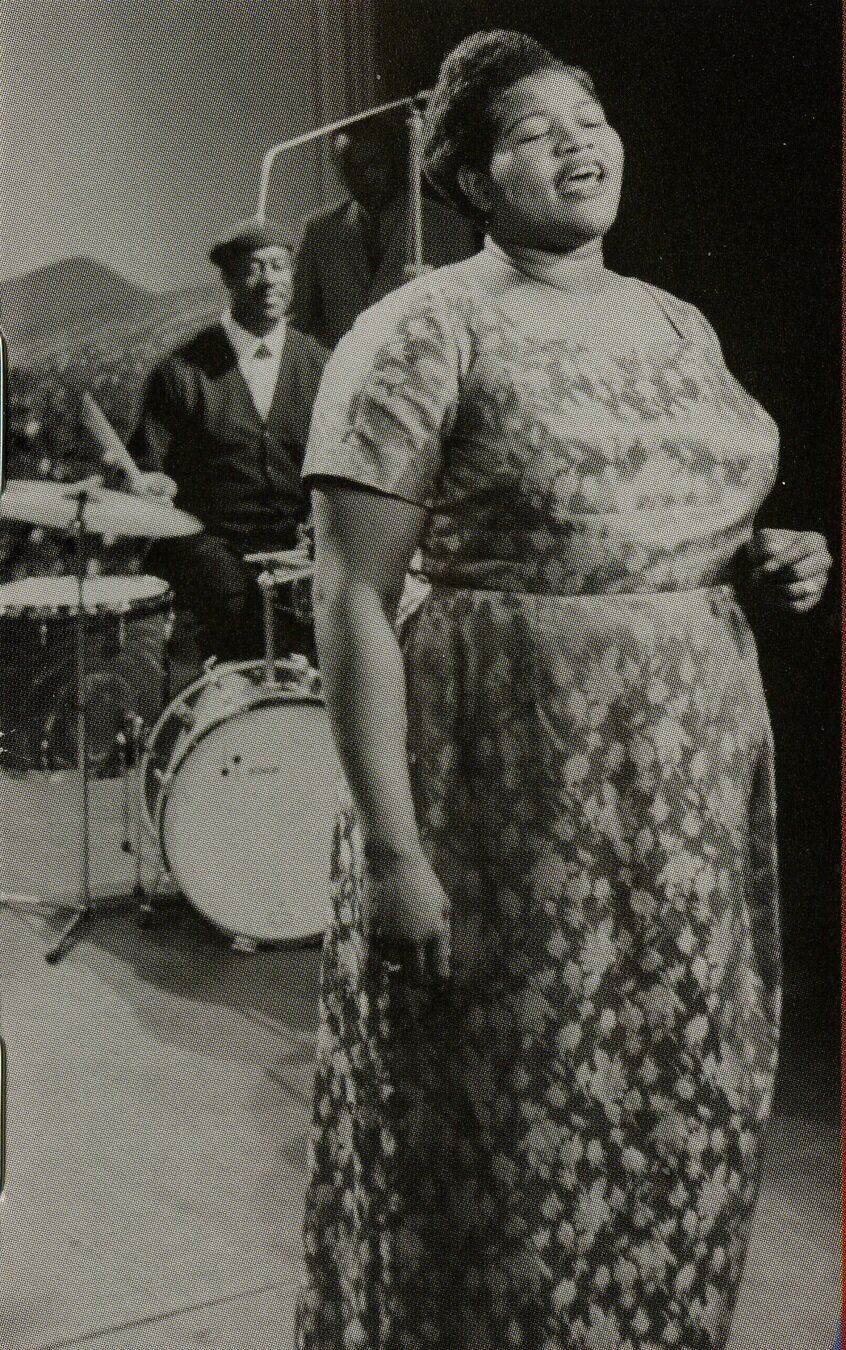 On the right of this slide, a black-and-white vertical photo depicts a full-frontal view of Big Mama Thornton wearing a floral dress, her right hand by her side; she is clearly singing, backed by a drummer on her right.