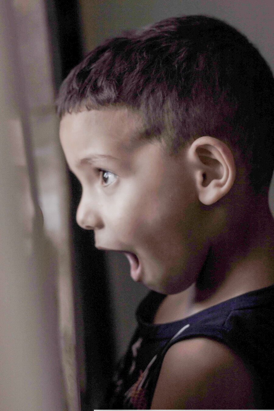 Surprised boy looking out window