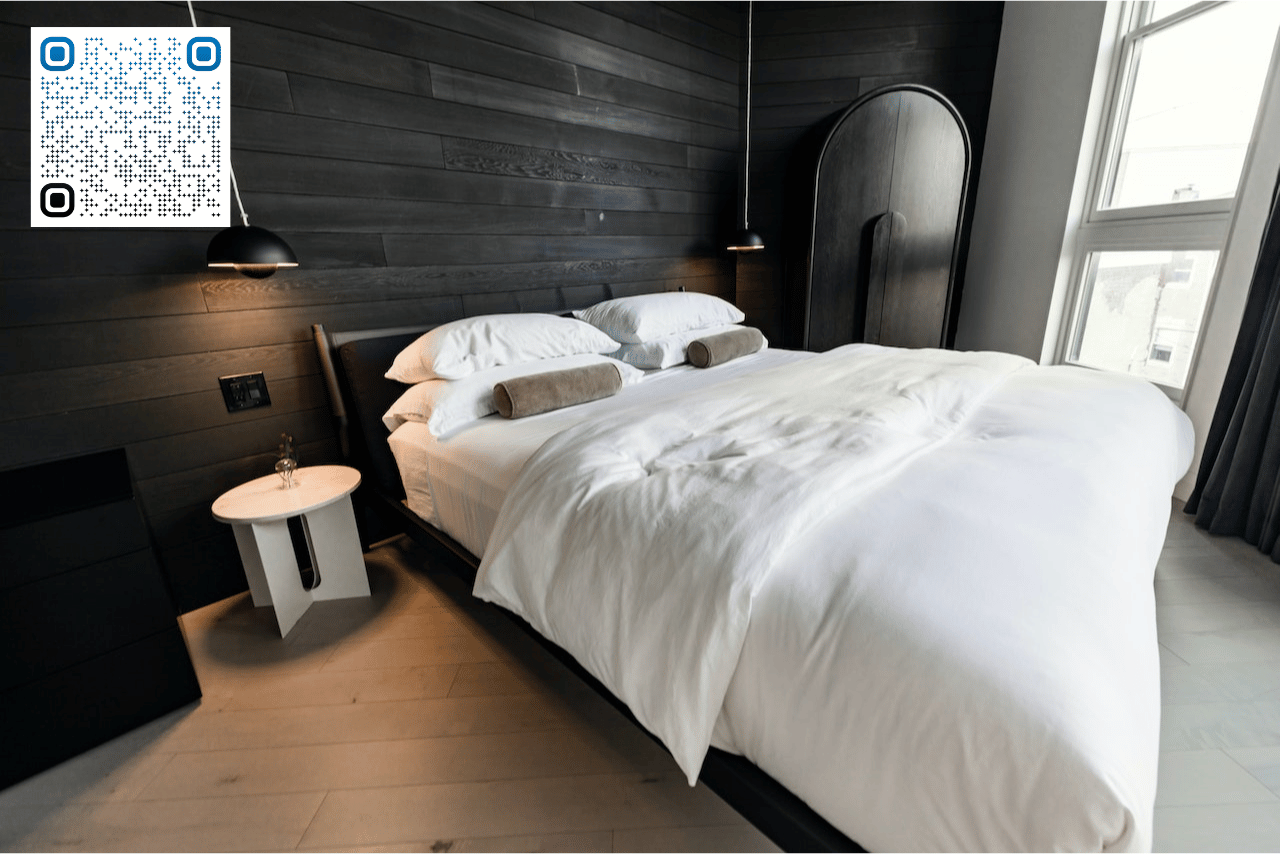 Beautiful Airbnb bedroom with black accent wall and white bed sheets. Designs like these tend to achieve higher incomes than an airbnb calculator estimates