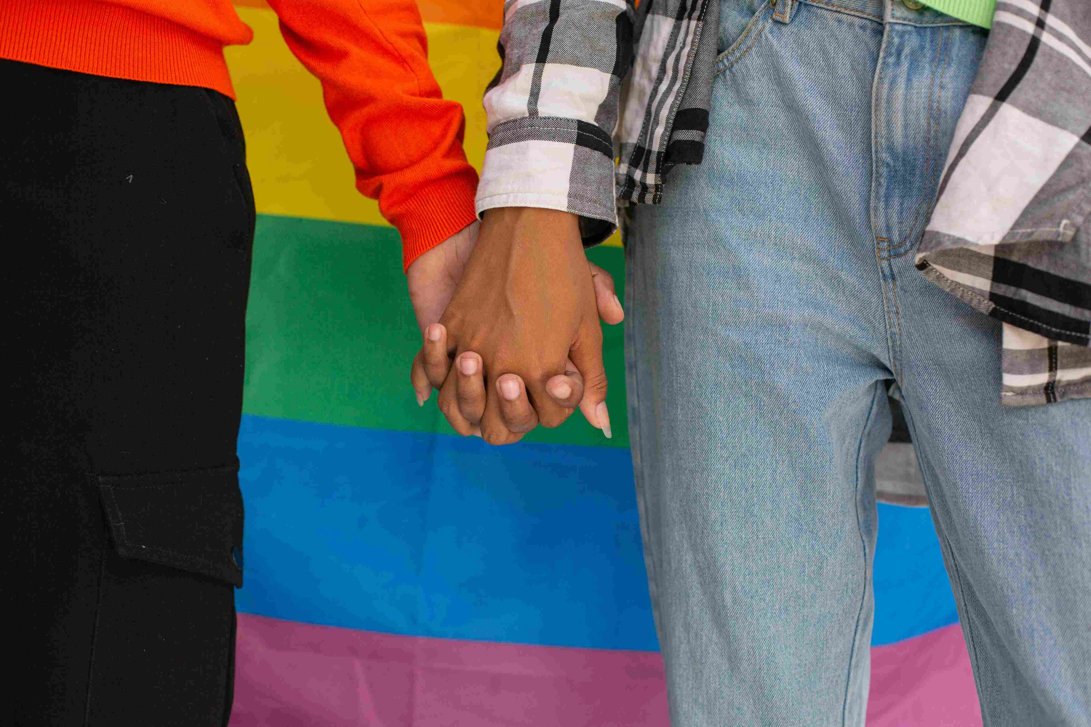 Close up of hands holding a pride flag