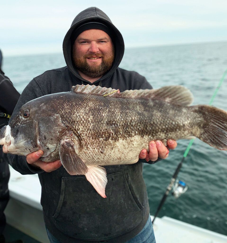Angler holding up blackfish on a boat