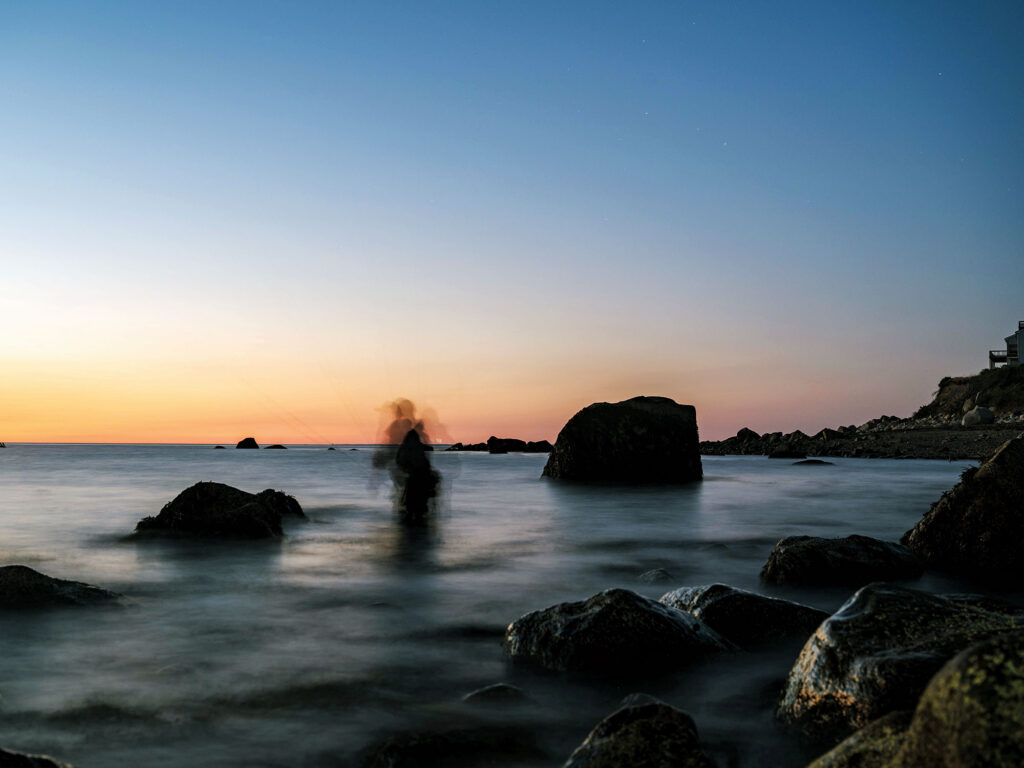 Angler fishing for striped bass at sunrise