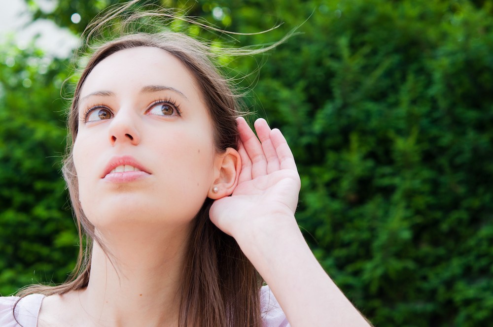 anxious looking woman holding a hand to ear