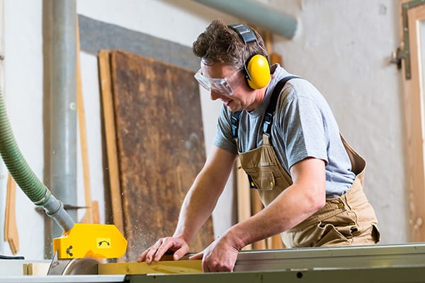 man cutting wood wearing over-the-head ear protection