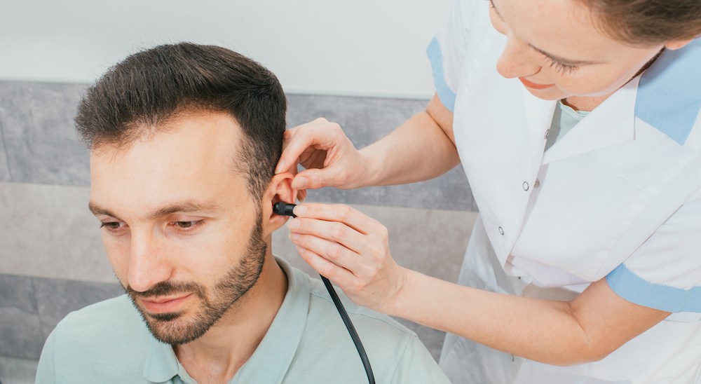audiologist testing the hearing ability of hearing patient