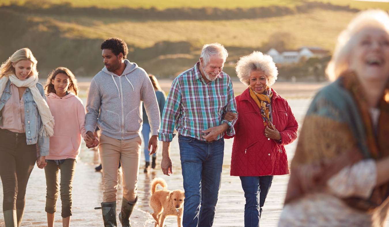 active multi generation familiy walking along shore