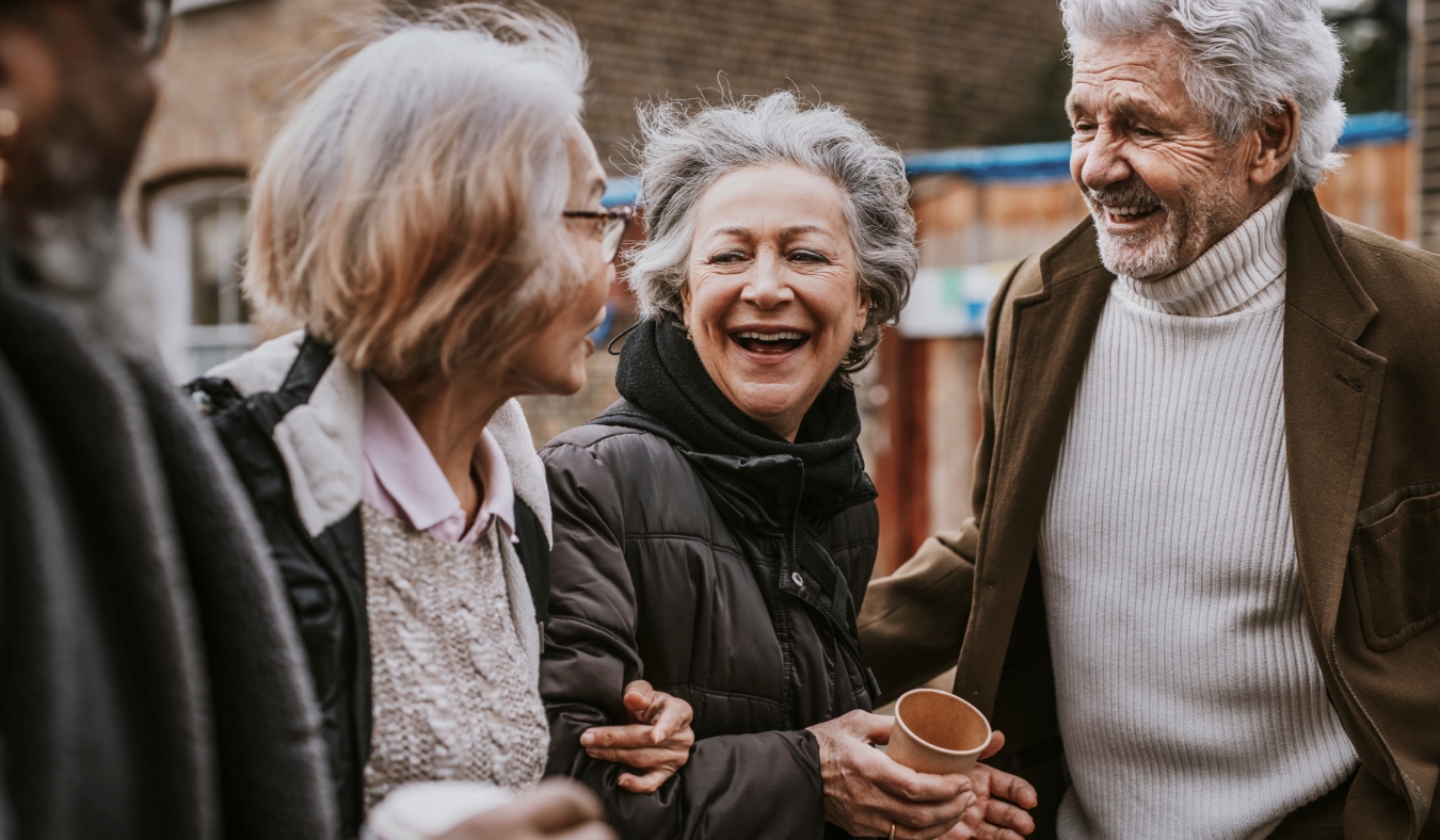 diverse senior friends laughing drinking coffee during autumn weather