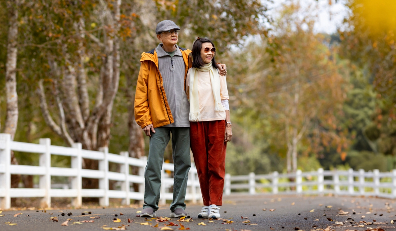 senior couple walking together in the public park during with fall