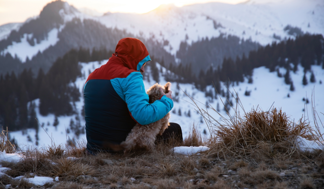 man with dog in the snowy mountains