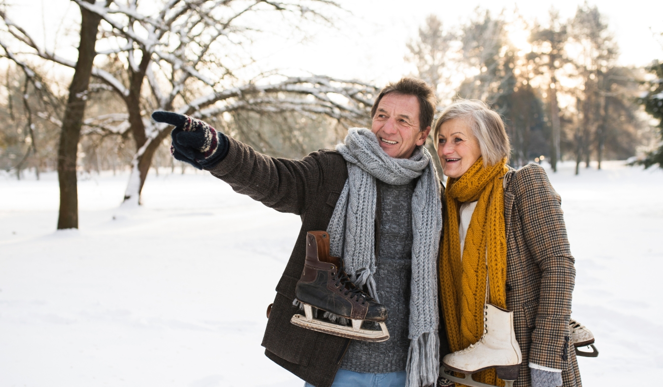 senior couple in winter nature with ice skates going to rink