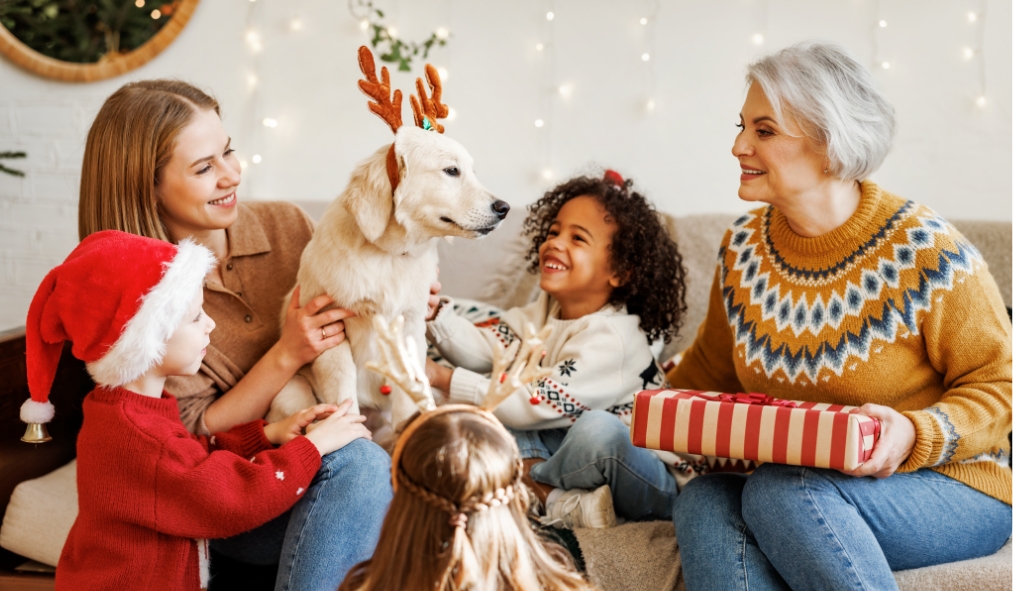 events christmas grandchildren laughing at dog with antlers grandmother holding present