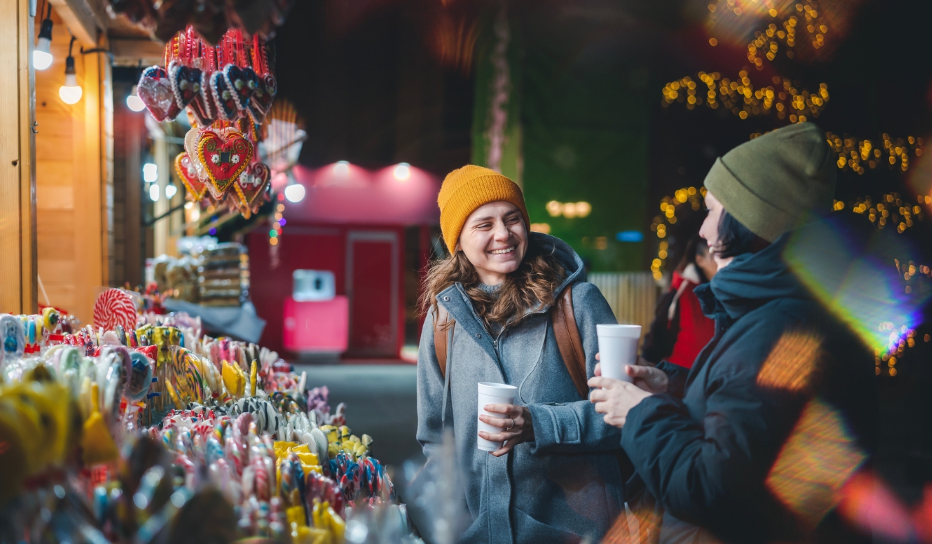 happy friends walking through holiday market