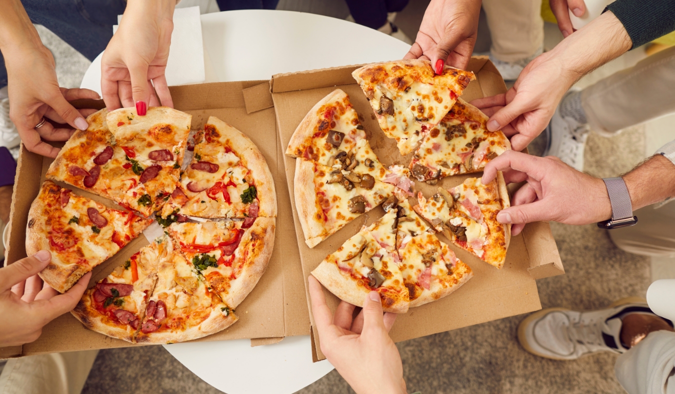 events people grabbing pizza slices from boxes