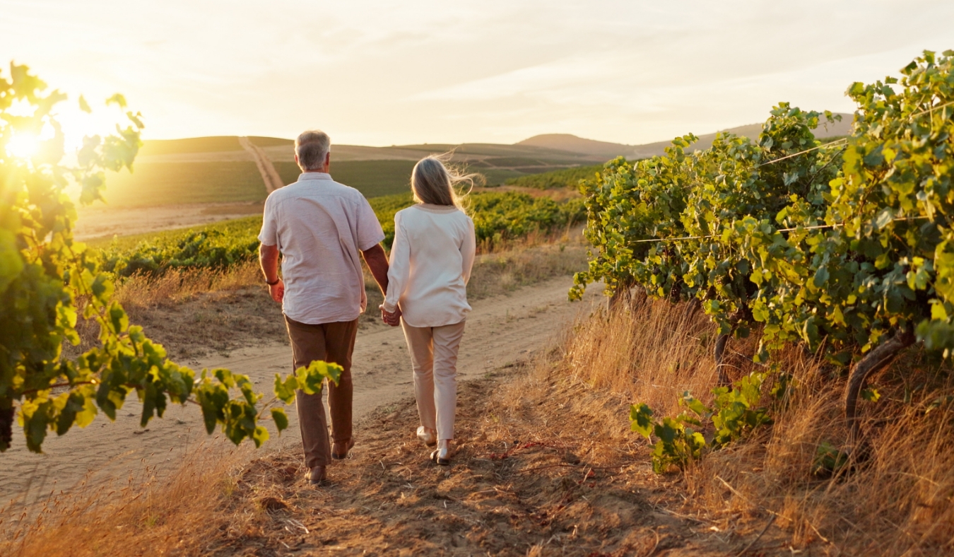 senior couple walking along mountainside at sunset