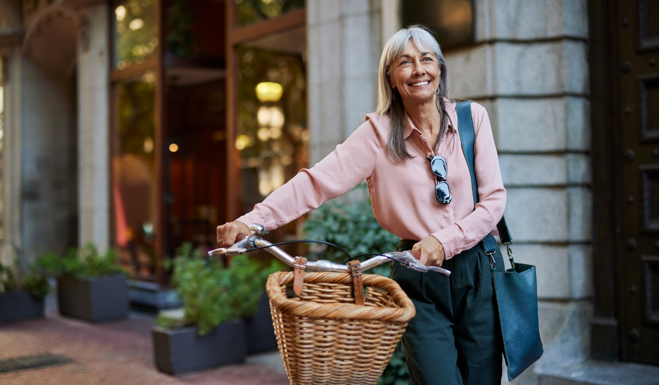 senior woman walking bike in downtown city