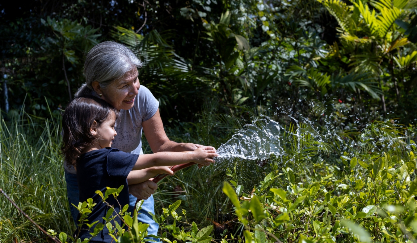 grandmother watering plants with grandchild