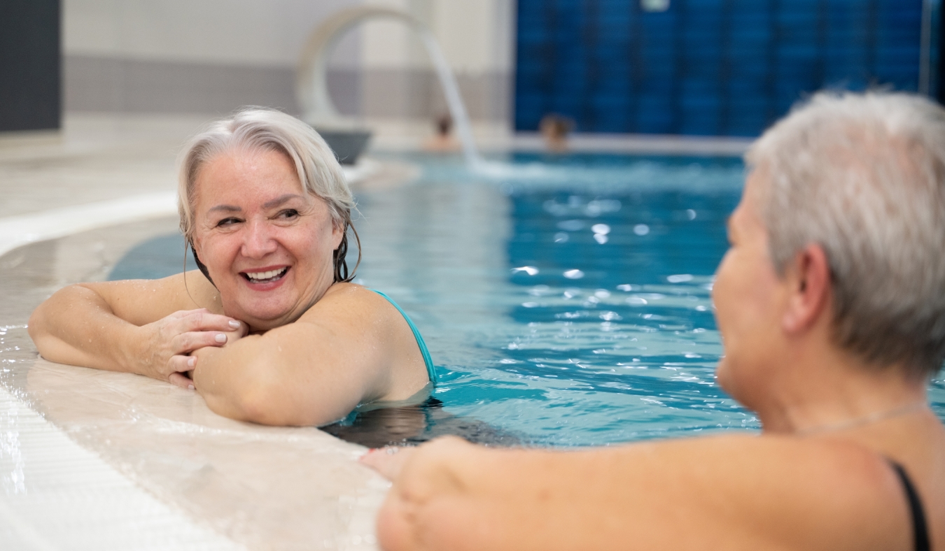 two smiling senior women enjoying leisure time in an indoor swimming