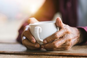 hands holding small white mug of coffee