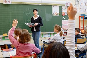 students raising hand to answer teachers question in classroom