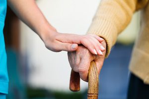 two hands touching on a walking cane