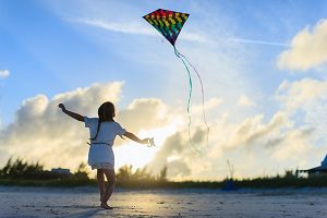 young child flying kite on sunny beach