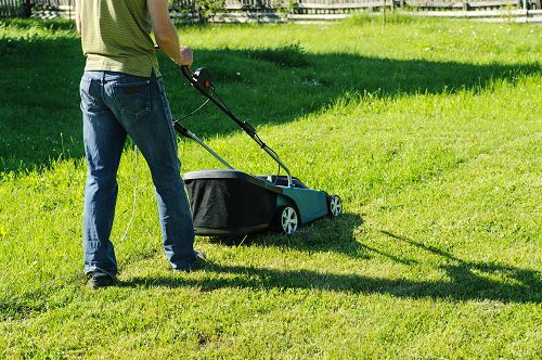 man mowing lawn outside during hot day