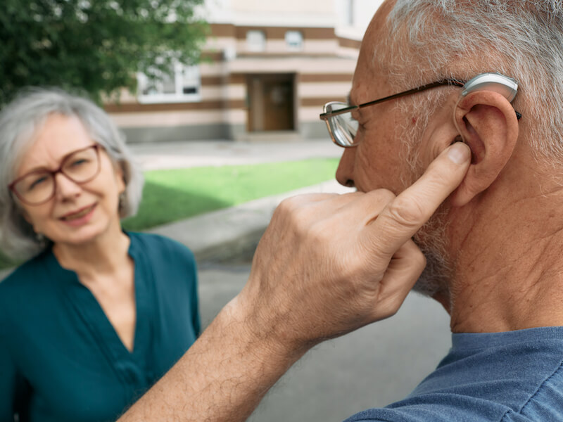 man adjusting settings on his hearing aids