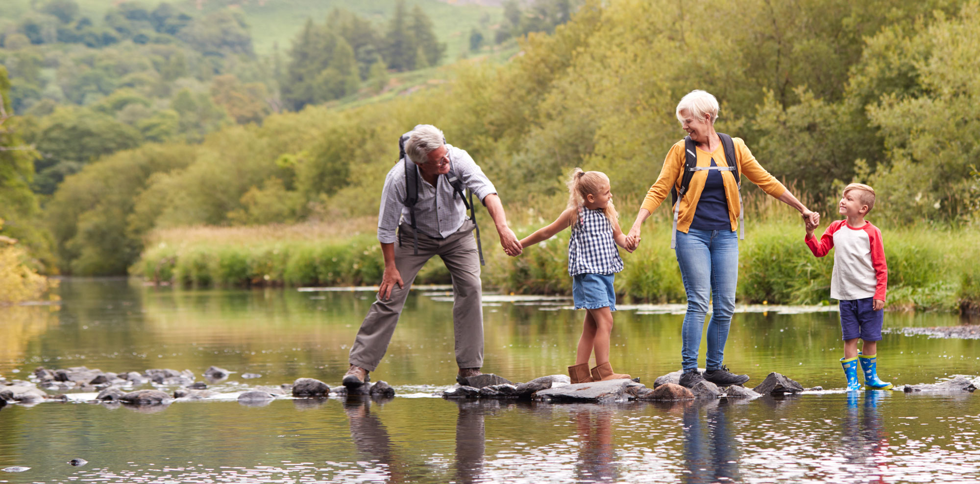 banner seasonal summer grandparents hiking stream with grandchild (1)
