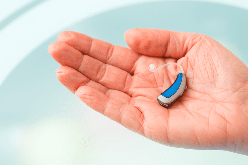 hand holding a blue bte hearing aid