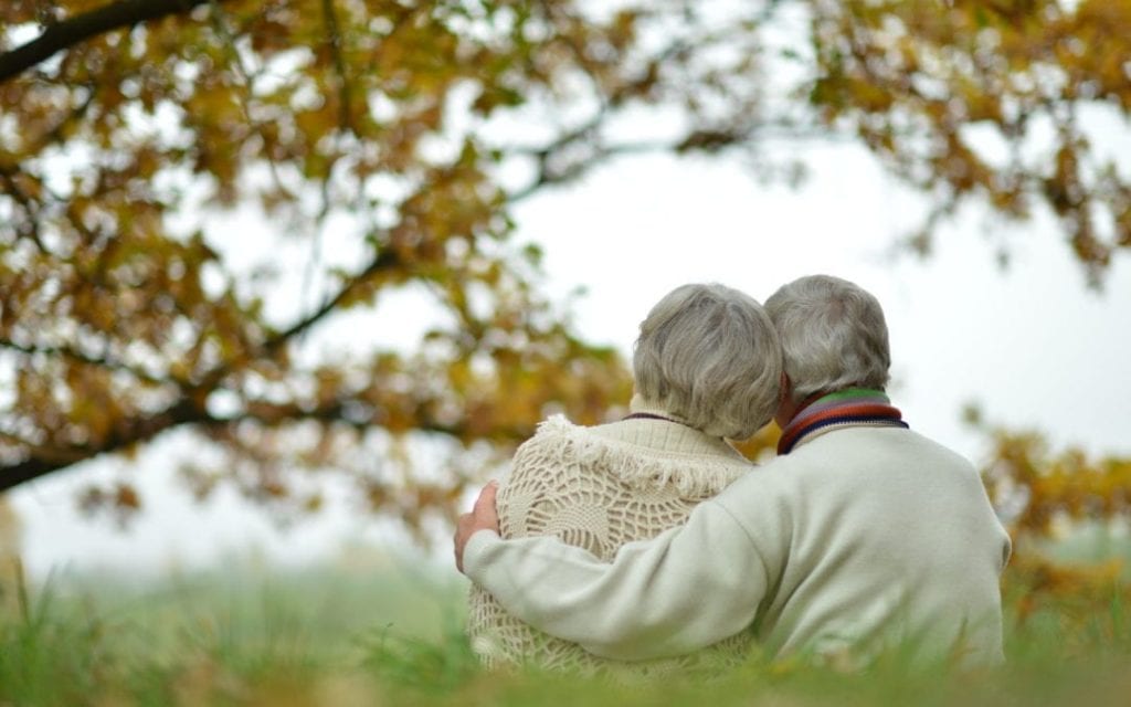 Elderly couple hugging sat otuside 1080x675 1