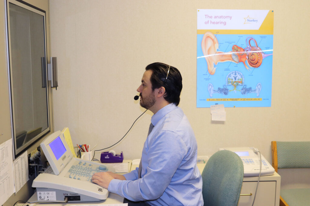 hearing care provider performing hearing test in booth