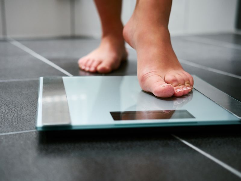 man stepping on a scale to measure weight