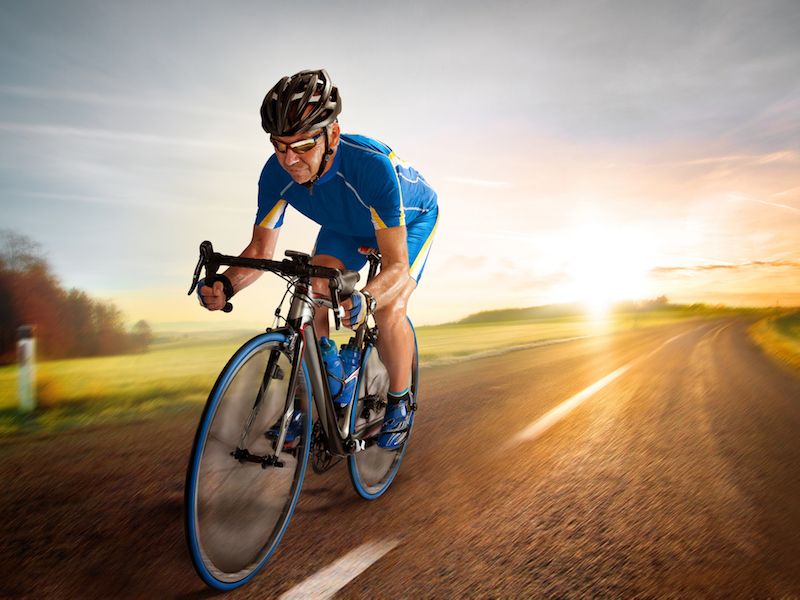 man riding a bike with sunset in background
