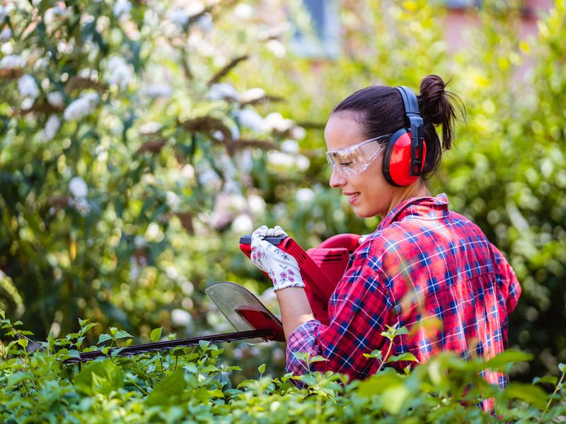 woman in garden with power tool and hearing protection