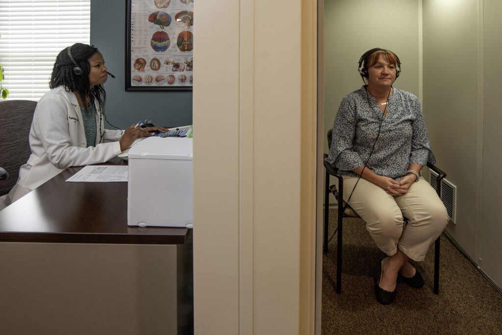 Hearall TaRonda Clark AuD preforming hearing test with patient in booth 75C2395