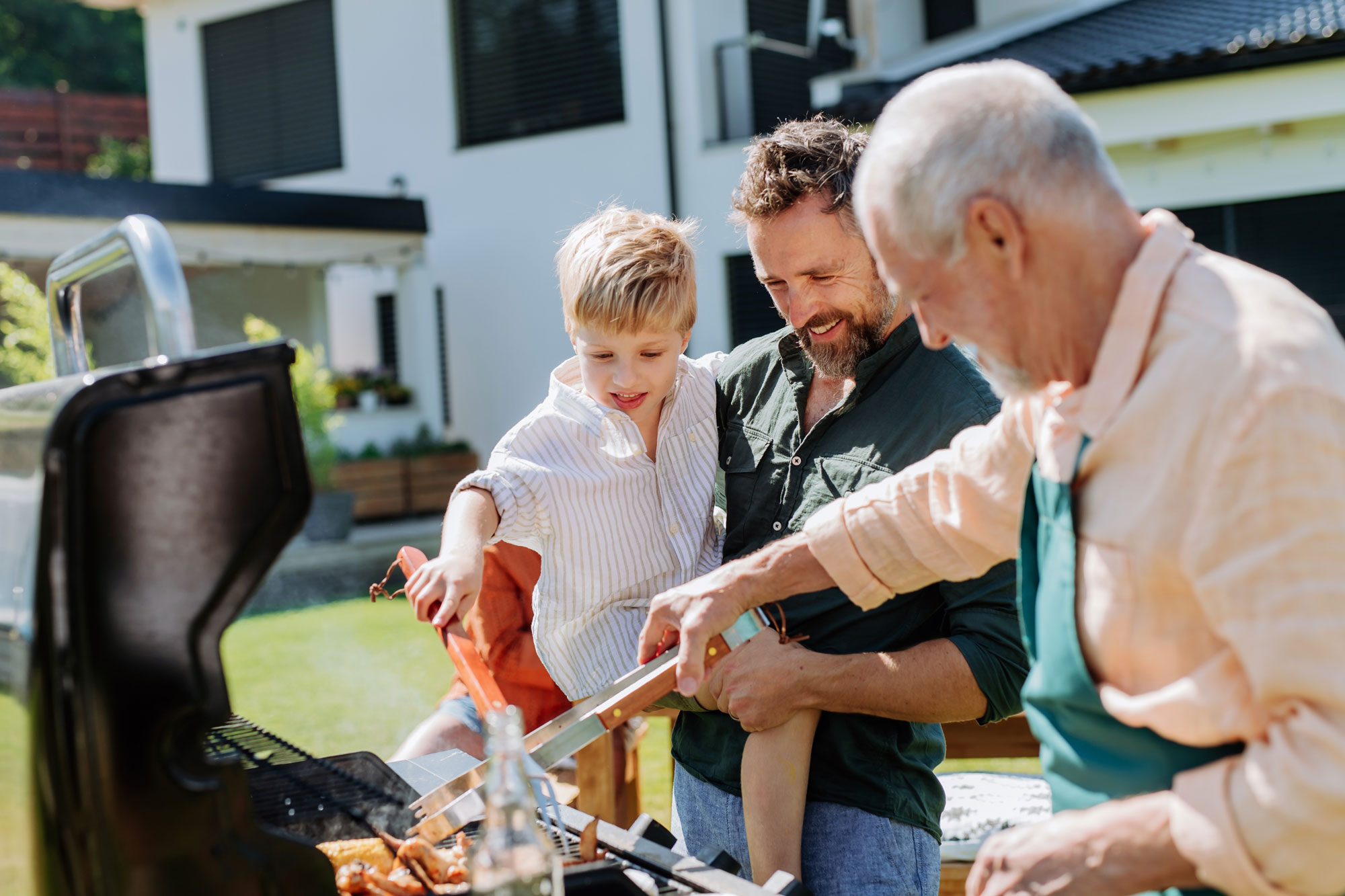 father grandson and grandfather grilling outside on beautiful day