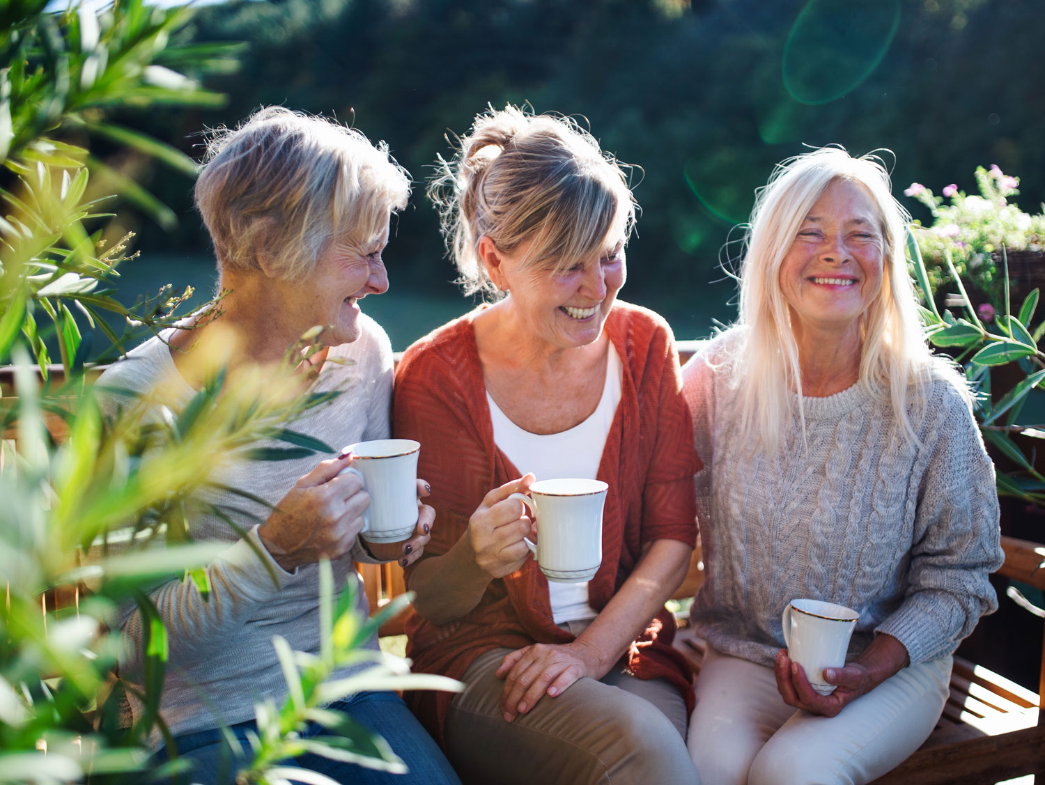 group of friends laughing drinking tea outside