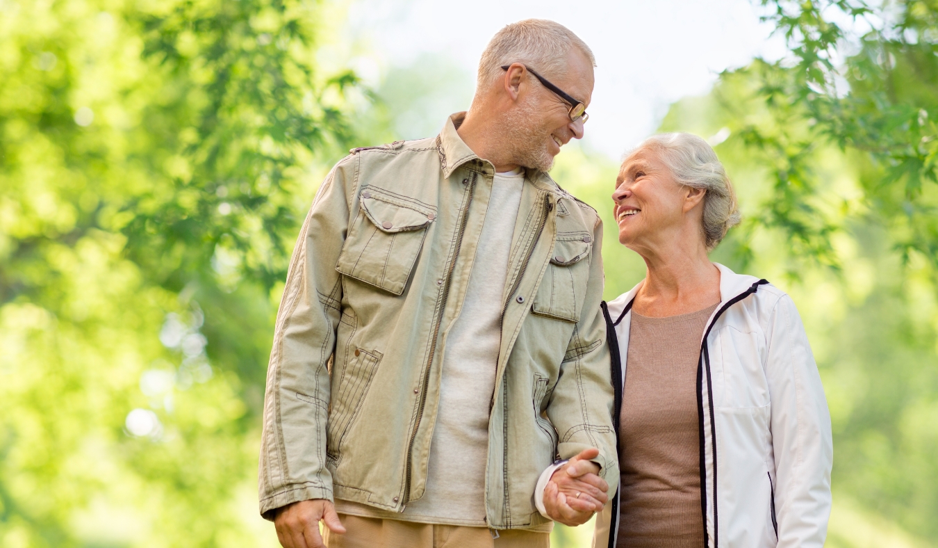 happy senior couple holding hands over green natural background