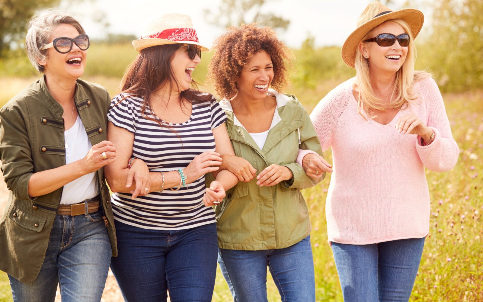 Group Of Mature Females Friends Walking Along Path Through Yurt Campsite