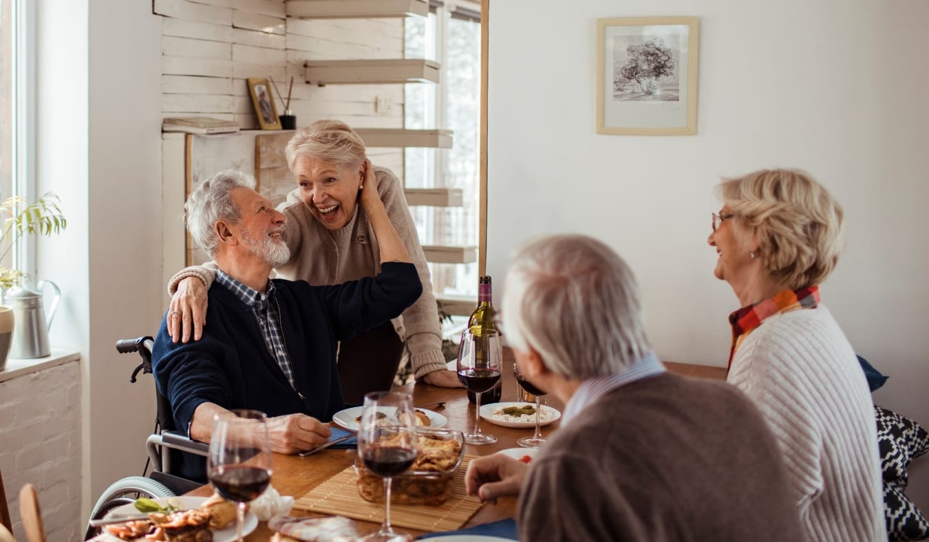 senior friends laughing enjoying a meal inside on a cold day