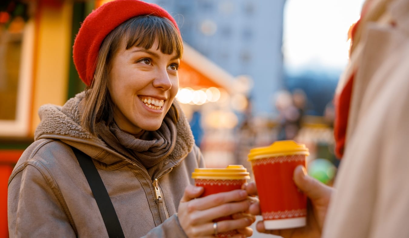 woman warming hands with hot drink outside