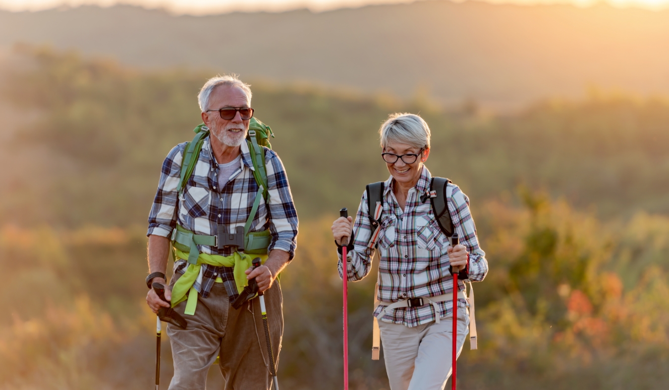 Active senior Caucasian couple hiking in mountains with backpacks and hiking poles