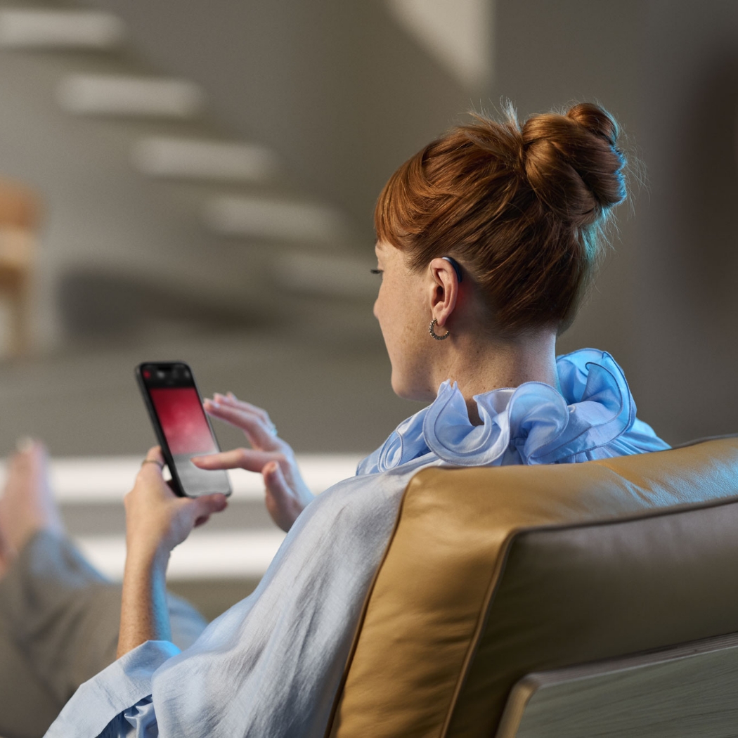 ReSound Vivia lifestyle woman connecting hearing aids with phone app
