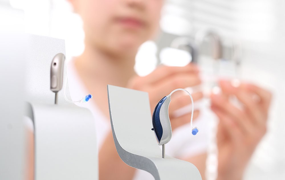 two silver and blue hearing aid devices on display on hearing clinic